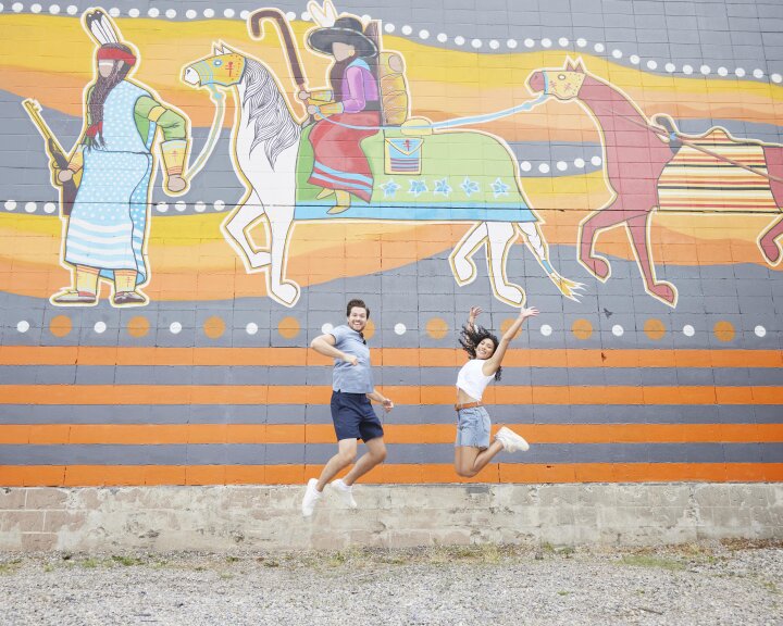 a couple jumping in front of a mural in calgary