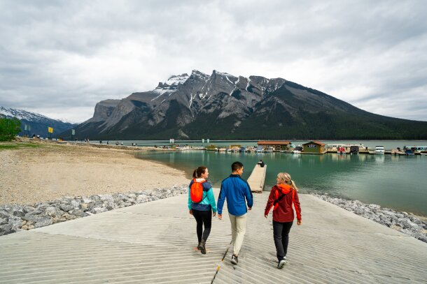 Two women and a man walk towards the dock at Lake Minnewanka.