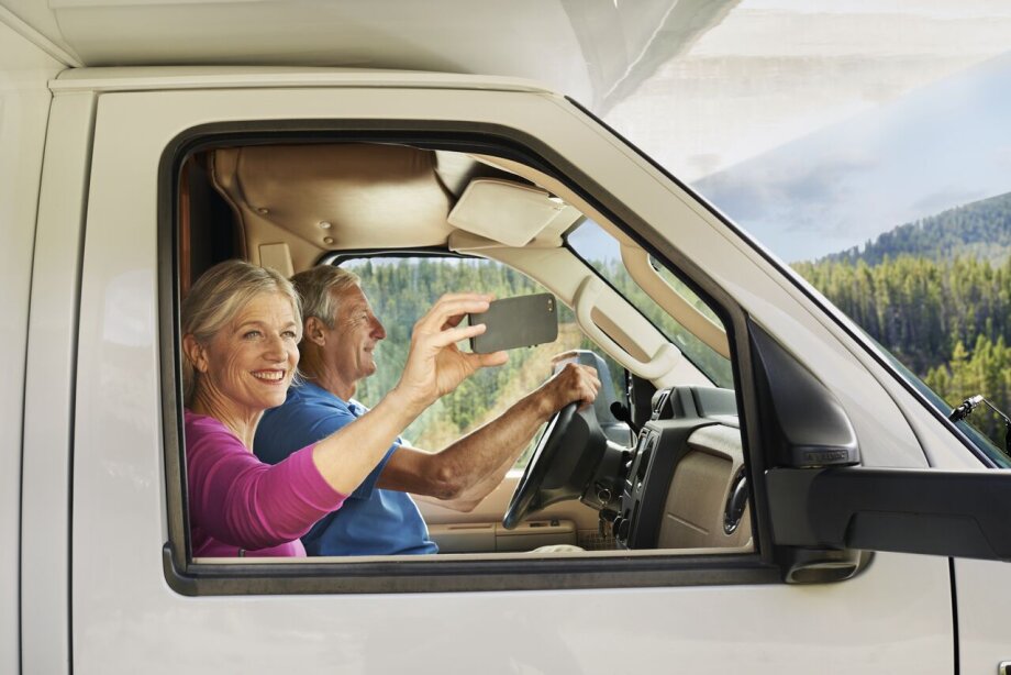 Senior couple driving in RV, taking a selfie