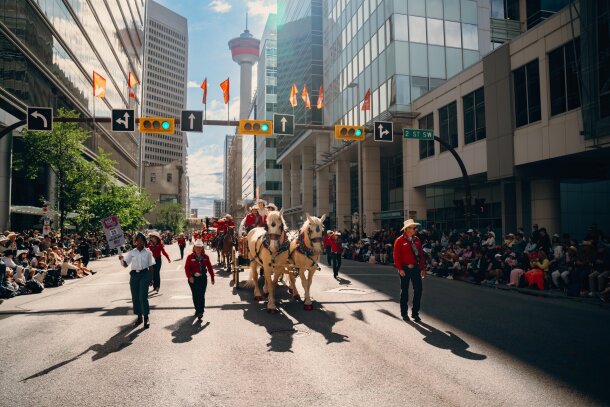 People on a carriage and walking during the Stampede Parade.