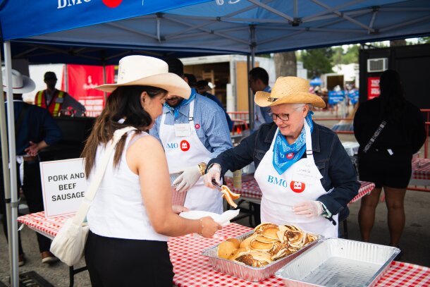 A woman serving another woman pancakes at a Stampede breakfast.