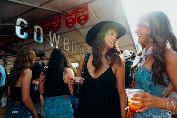 Two girls with drinks partying at Cowboys tent