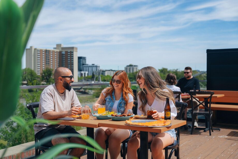 A group of friends eating pizza at Connie & John's rooftop patio.