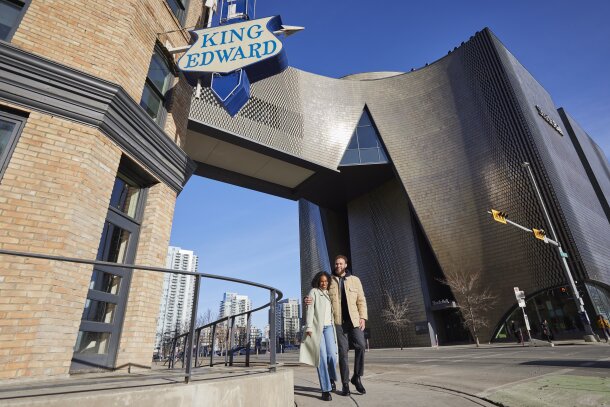 Couple walking by the King Eddy across Studio Bell