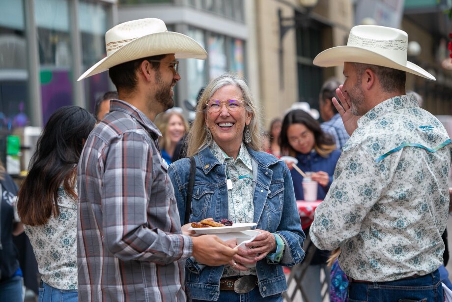 3 people dressed in western wear chatting and eating a pancake breakfast