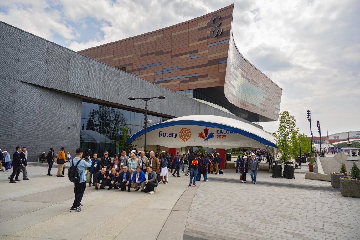 Group of Rotary attendees posing for a photo in front of a large entrance gate