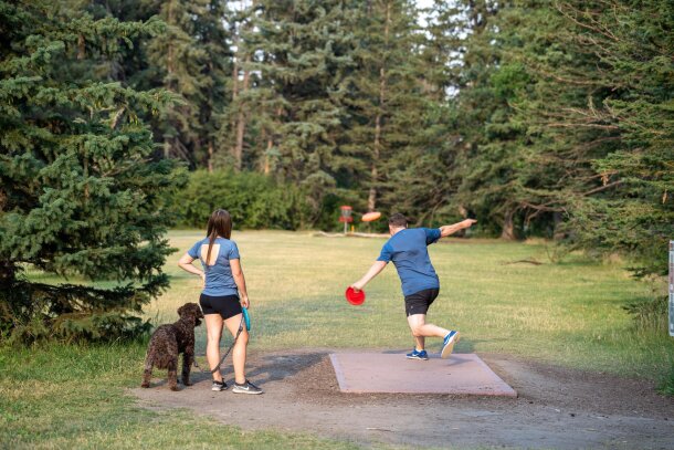couple and their dog playing disc golf in Baker park