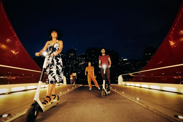 People scootering and roller-skating across the Peace Bridge in Calgary at Night