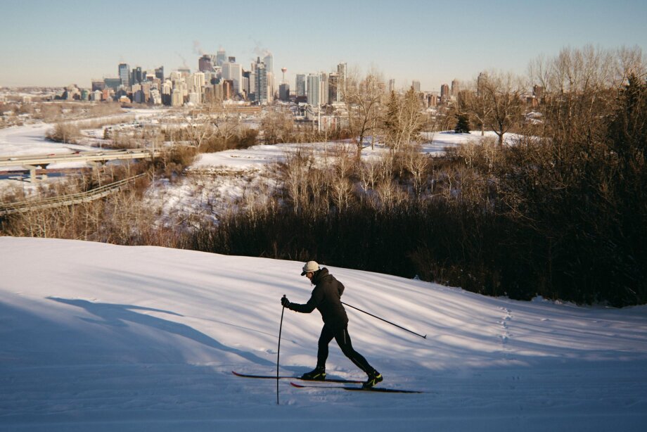 A man cross-country skiing at Shaganappi Golf Course with the Calgary skyline in the background