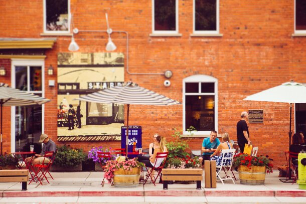 People sitting at patio tables on a sidewalk in the Kensington neighborhood in Calgary