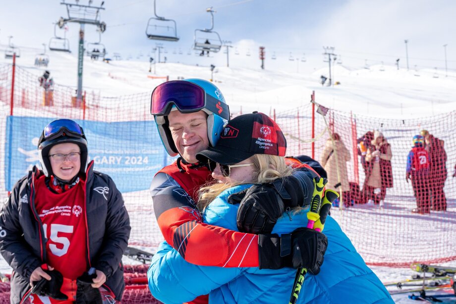 Special Olympic skiing competitor giving hug on the ski hill