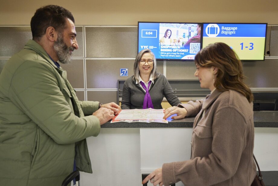 Visitor experience staff member helping two travellers.