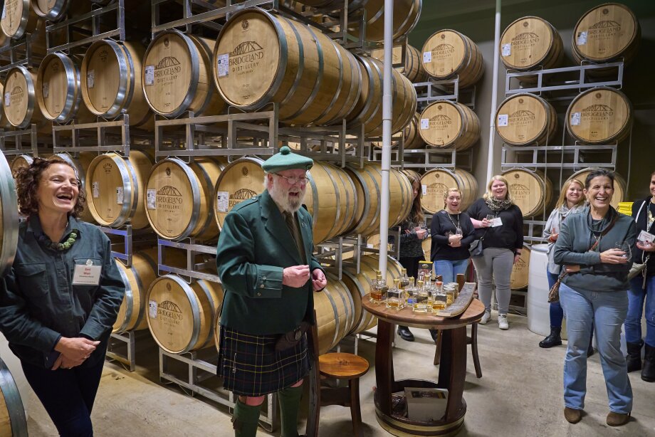 Man dressed in a kilt hosting a whiskey tasting in the barrel room of a distillery